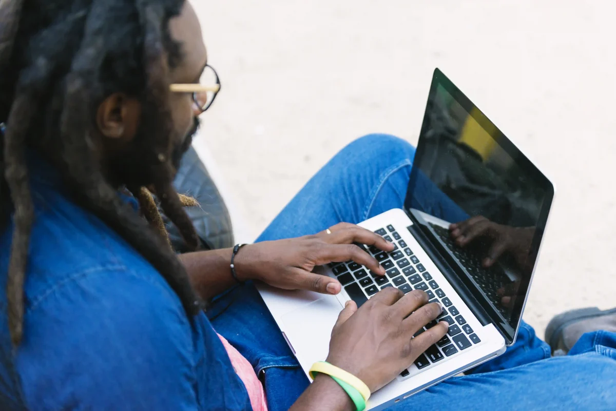 Homem usando notebook ao ar livre enquanto faz um curso de licitação online.